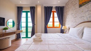 A hotel room with a large bed, a bedside table with a lamp, a TV, and a view of the outdoors through a window. - CIEL ROSE HOTEL (Phu Quoc)