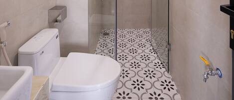 A modern bathroom with a shower, toilet, and sink.
