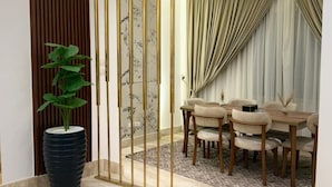 Un intérieur moderne comprenant un coin repas, une plante en pot et un élément de séparation décoratif.