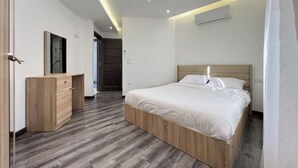 Une chambre à coucher moderne avec un lit en bois, une commode en bois et un couloir menant à une autre pièce.