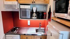 Une cuisine compacte équipée d’un four à micro-ondes, d’une machine à café et d’un lave-vaisselle.