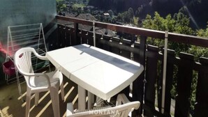 Un balcon avec une table et des chaises, donnant sur un paysage montagneux.