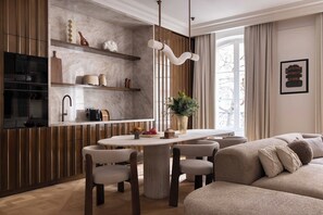 Eine moderne Küche mit Marmorarbeitsplatte, Holzschränken und einem Essbereich mit rundem Tisch und Stühlen.