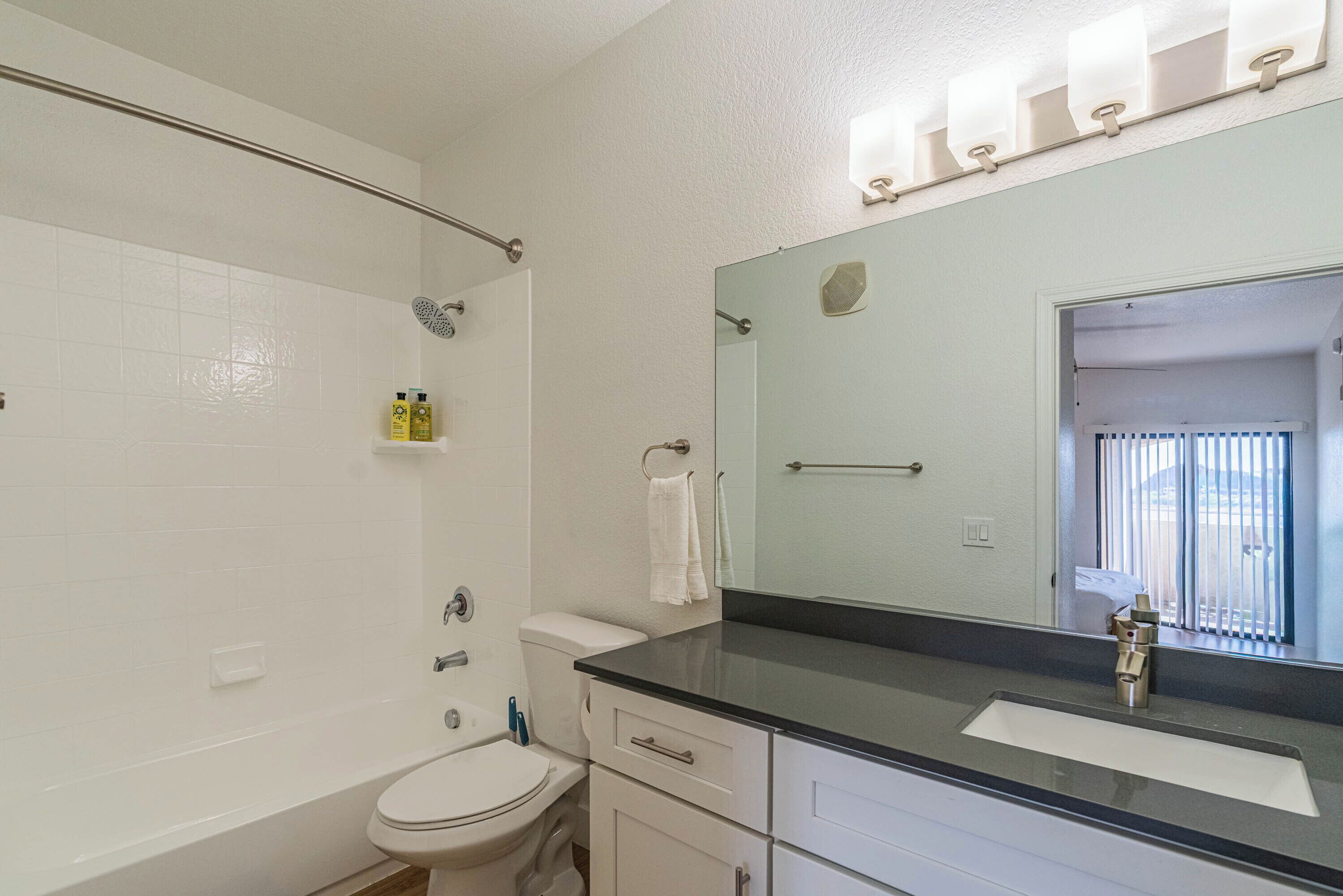 Ein Badezimmer mit Toilette, Waschbecken, Spiegel und Duschbereich.
