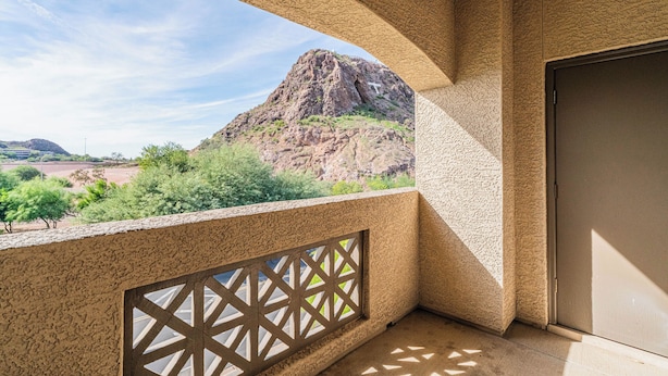 Uma varanda com vista para uma montanha rochosa, uma porta e um muro texturizado.