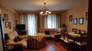 Uma sala de estar com sofá, mesa de jantar e televisão.