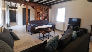 En stue med sofa, sofabord og fjernsyn. En trappe er synlig i baggrunden.