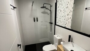 A modern bathroom with a glass-enclosed shower, a white toilet, and a wooden vanity with a sink.