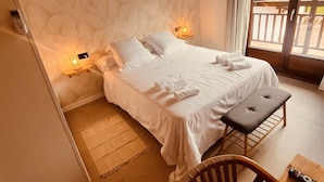 A bedroom with a bed, bedside lamps, a wooden bench, and a table.