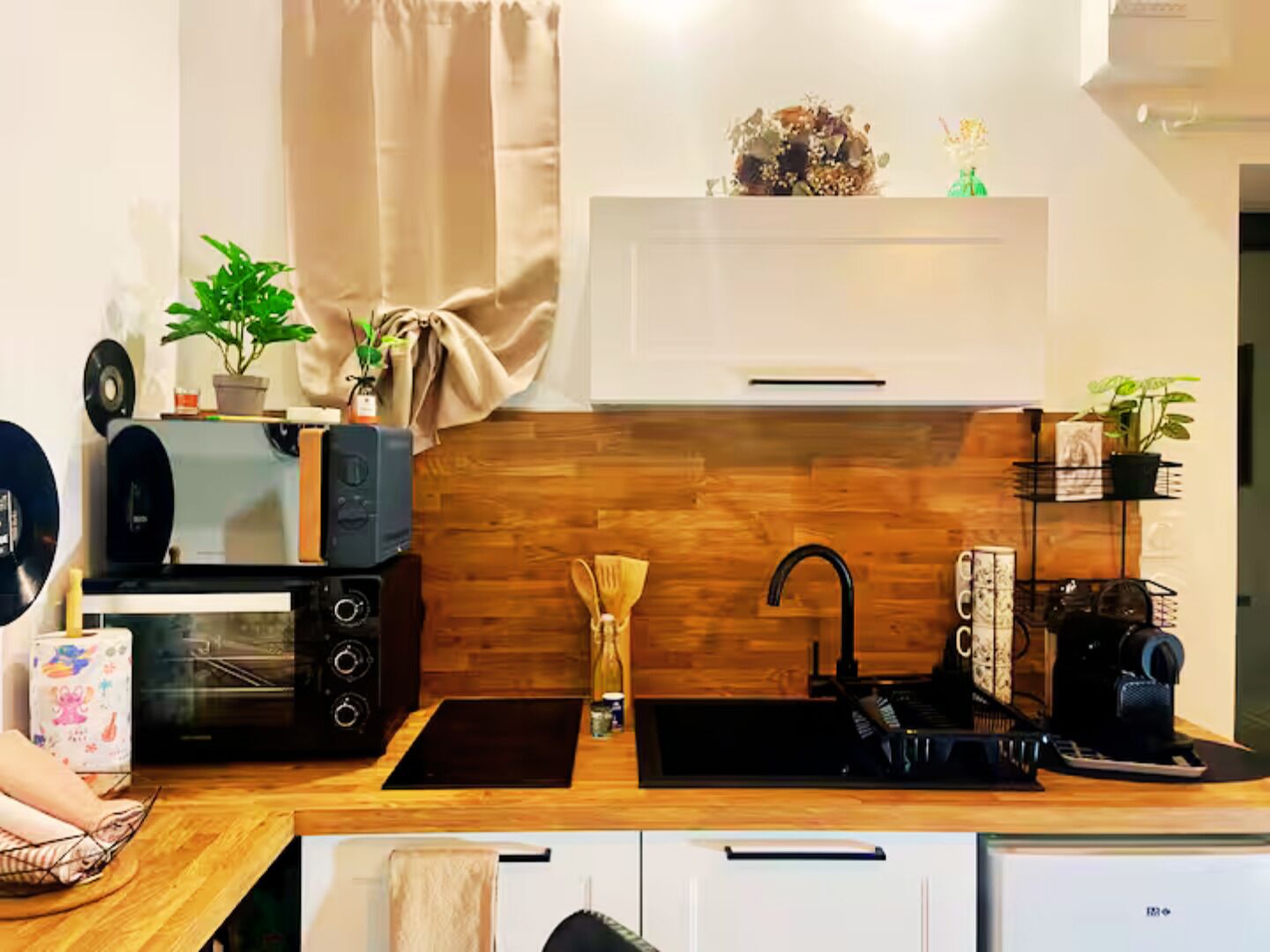 Une cuisine moderne dotée d’un plan de travail en bois, d’un évier noir, d’un four encastré et d’une armoire blanche.