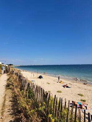 A sandy beach with a wooden fence, a tent, and people relaxing. - Family home within walking distance of the beach! (Sarzeau)
