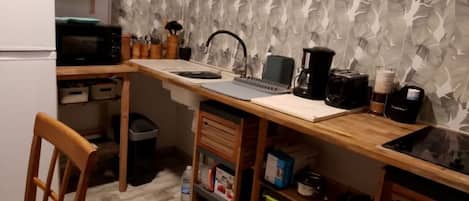 Une petite cuisine équipée d’un four à micro-ondes, d’une machine à café et d’un ordinateur portable posé sur le comptoir.