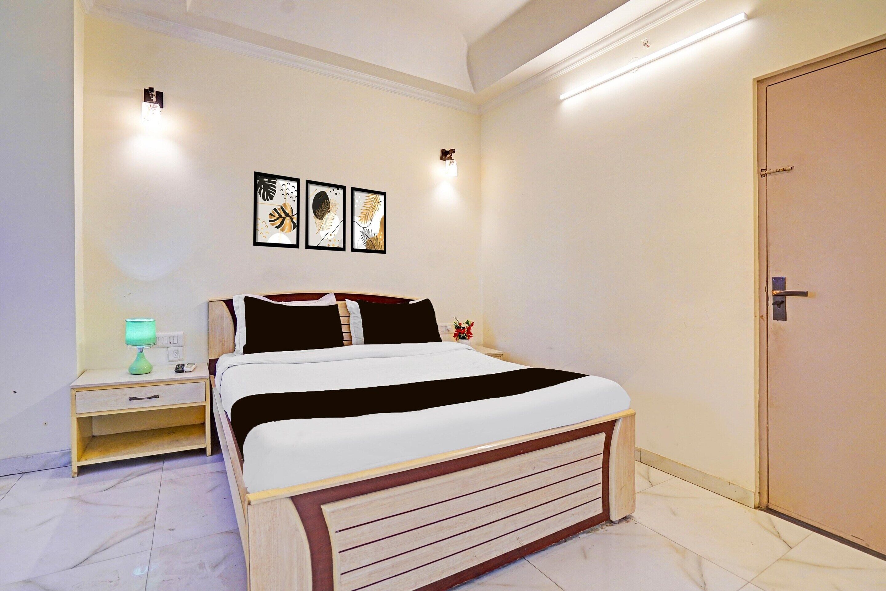 A bedroom with a bed, nightstand, lamp, and wall art.