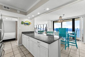 A kitchen with a large island, white cabinets, and a view of the ocean. - PCB Gulf Front Paradise at Edgewater deluxe 2/2 in Tower 3 with balcony (Panama City)