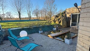 A patio with two blue chairs, a small pond, and a wooden deck. - Unusual gîte with spa & sauna - 15 min from Mont-St-Michel ✨ the starry sky✨ (Juilley)