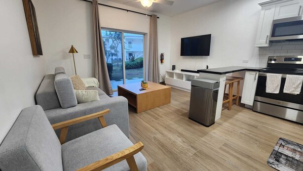 Un salon moderne avec un canapé gris, une table basse en bois et un téléviseur fixé au mur.