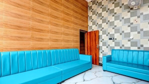 A room with two blue sofas, a wooden wall, and a marble floor.