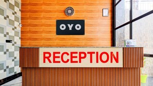 A reception desk with a sign that reads "RECEPTION" and a sign above it that says "OYO".