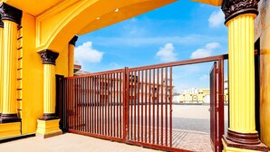 A gated entrance with yellow columns and a clear sky.