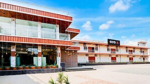 A hotel with a modern design, featuring multiple balconies and a spacious outdoor area with potted plants.