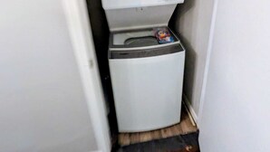 Un lavadero pequeño con lavadora y secadora apiladas.