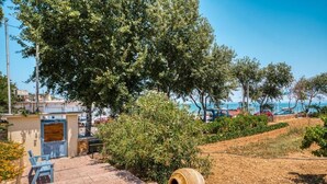 Un espace extérieur aménagé avec une petite construction, un grand arbre et une vue sur la mer.