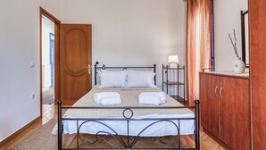 Un lit simple avec un cadre en métal, une armoire en bois et une porte donnant sur une autre pièce.