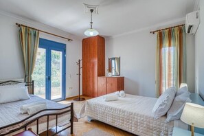 A bedroom with two beds, a wardrobe, a mirror, and a window with curtains.