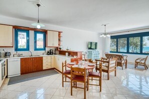 Cocina moderna con comedor, que incluye una isla grande, armarios de madera y vistas al mar.