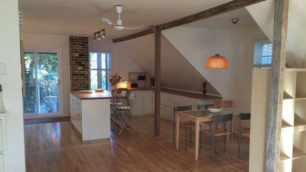 Een ruime keuken met een centraal eiland, een houten eettafel en een gezellige zithoek.