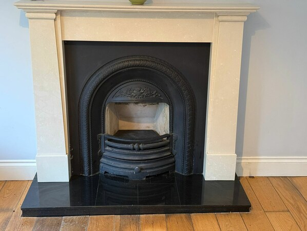 A fireplace with a black hearth and white mantel, set in a room with wooden flooring.