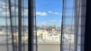 Vista a través de cortinas traslúcidas de un paisaje urbano con edificios y cielo despejado.