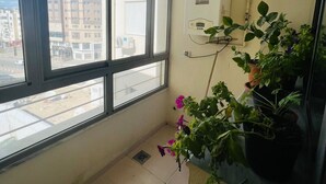 Un pequeño balcón con vista a edificios, un radiador blanco y plantas en macetas.