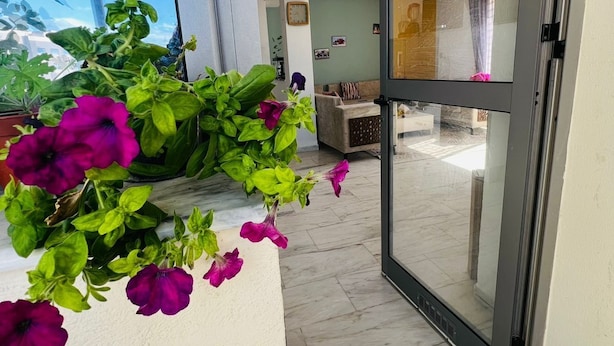 Un interior moderno con un piso de baldosas, un vidrio que da a un balcón y vistas al cielo.
