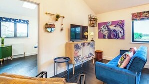 Una sala de estar acogedora con un sofá azul, un televisor y un cuadro en la pared.
