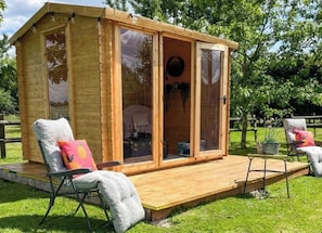 A wooden cabin with a glass door, a deck, and two chairs with cushions. - Lottie's Luxurious Lodge- luxury rural 2-bed cottage, peaceful walks & stays UK (Maidstone)