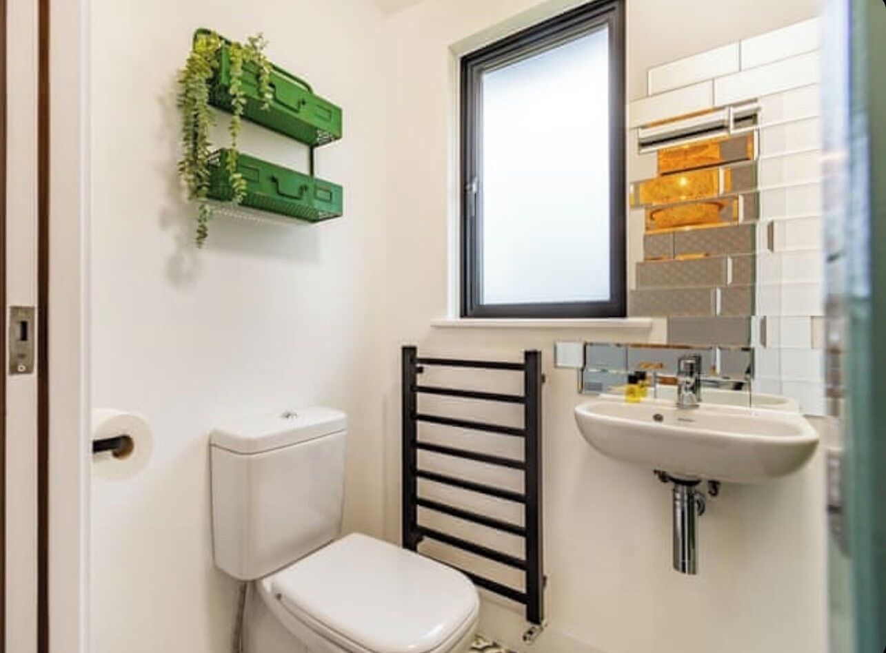 A small bathroom with a toilet, a sink, a towel rack, and a window.