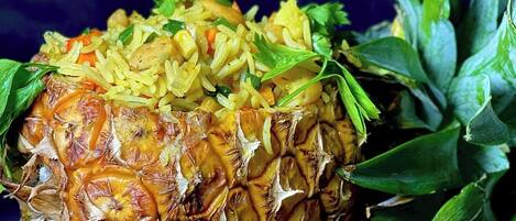 Uma abacaxi com um prato de arroz amarelo e legumes ao lado.