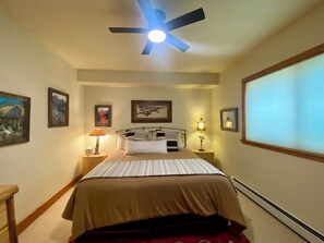 A bedroom with a bed, a ceiling fan, framed pictures on the walls, a bedside lamp, and a window with blinds. - Bring your family and enjoy a 3-bedroom condo in charming Crested Butte (Crested Butte)