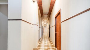 A hallway with patterned flooring, wooden doors, and white walls.
