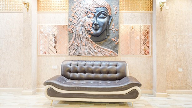 A modern lobby with a large abstract painting, a plush leather sofa, and a patterned floor.