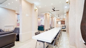 A conference room with a long table, chairs, a sofa, and ceiling fans.