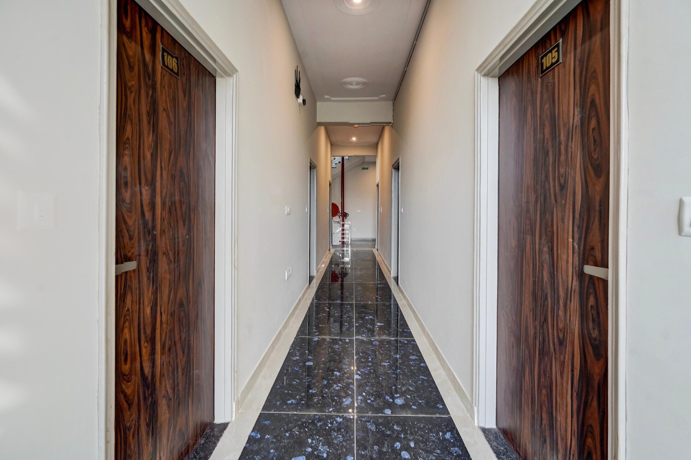 A hallway with dark wood doors, numbered 106 and 105, leading to a room.