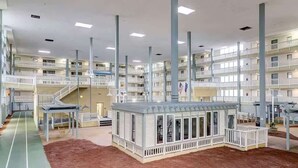 Ein mehrstöckiges Hotel mit Balkonen, einem zentralen Atrium und einer kleinen Außenanlage mit einer Dachterrasse.