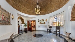 Eine geräumige Lobby mit hoher Decke, einem großen Kronleuchter und einem polierten Marmorboden.