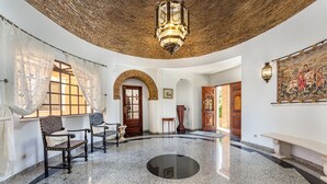 Eine geräumige Lobby mit einem glänzenden Granitboden, einem runden schwarzen Spiegel und einer traditionellen Holztür.