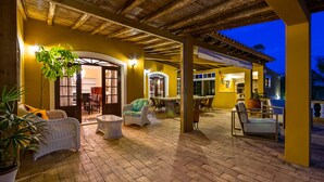 Ein Patio im Freien mit Korbmöbeln, einem Esstisch und Blick ins Innere.