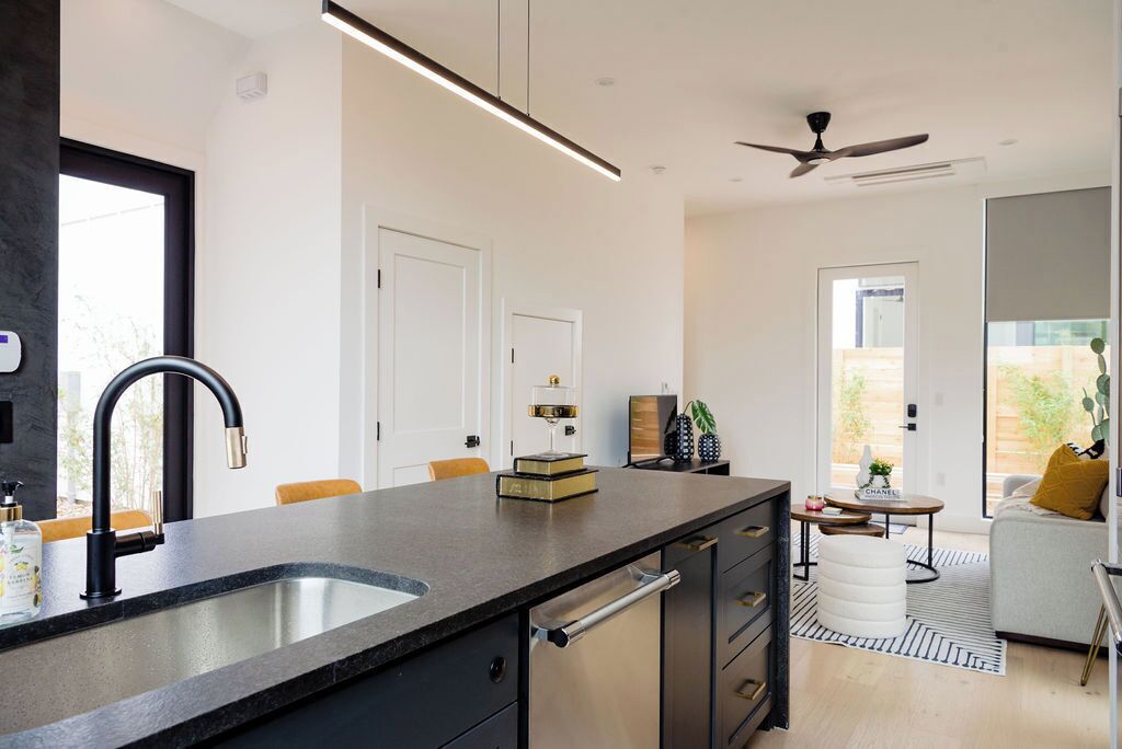 A modern kitchen with a large island, a built-in sink, and a ceiling fan.