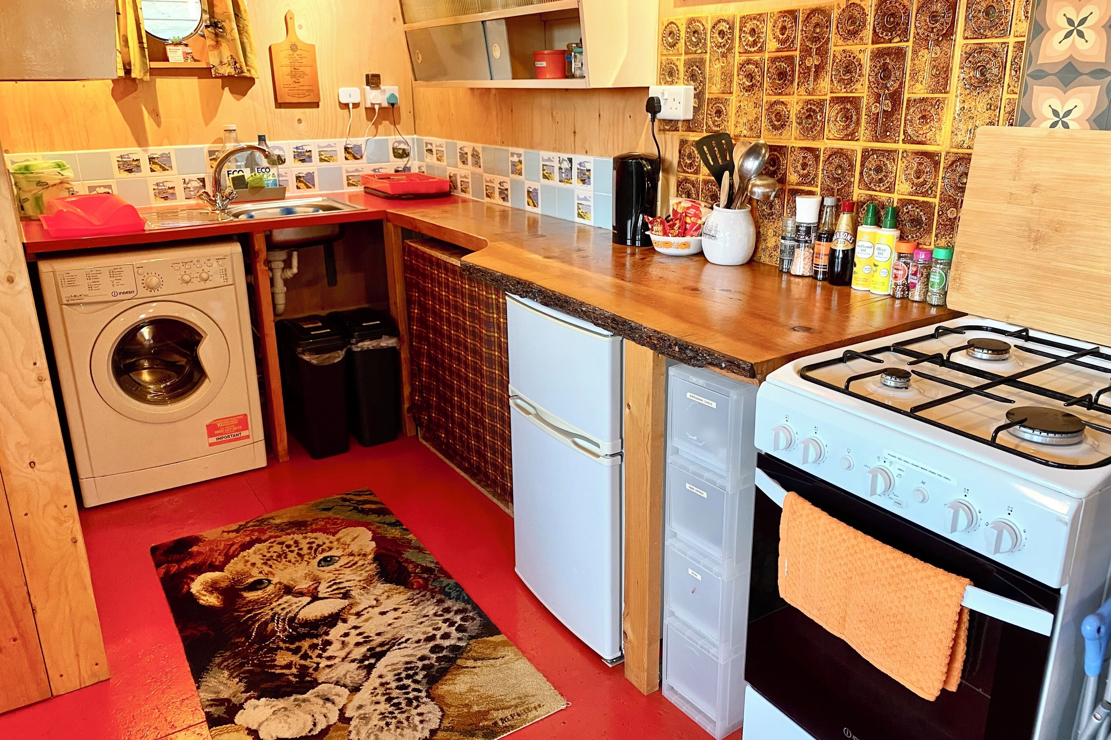 Een kleine keuken met een wasmachine, vaatwasser, koelkast en fornuis.