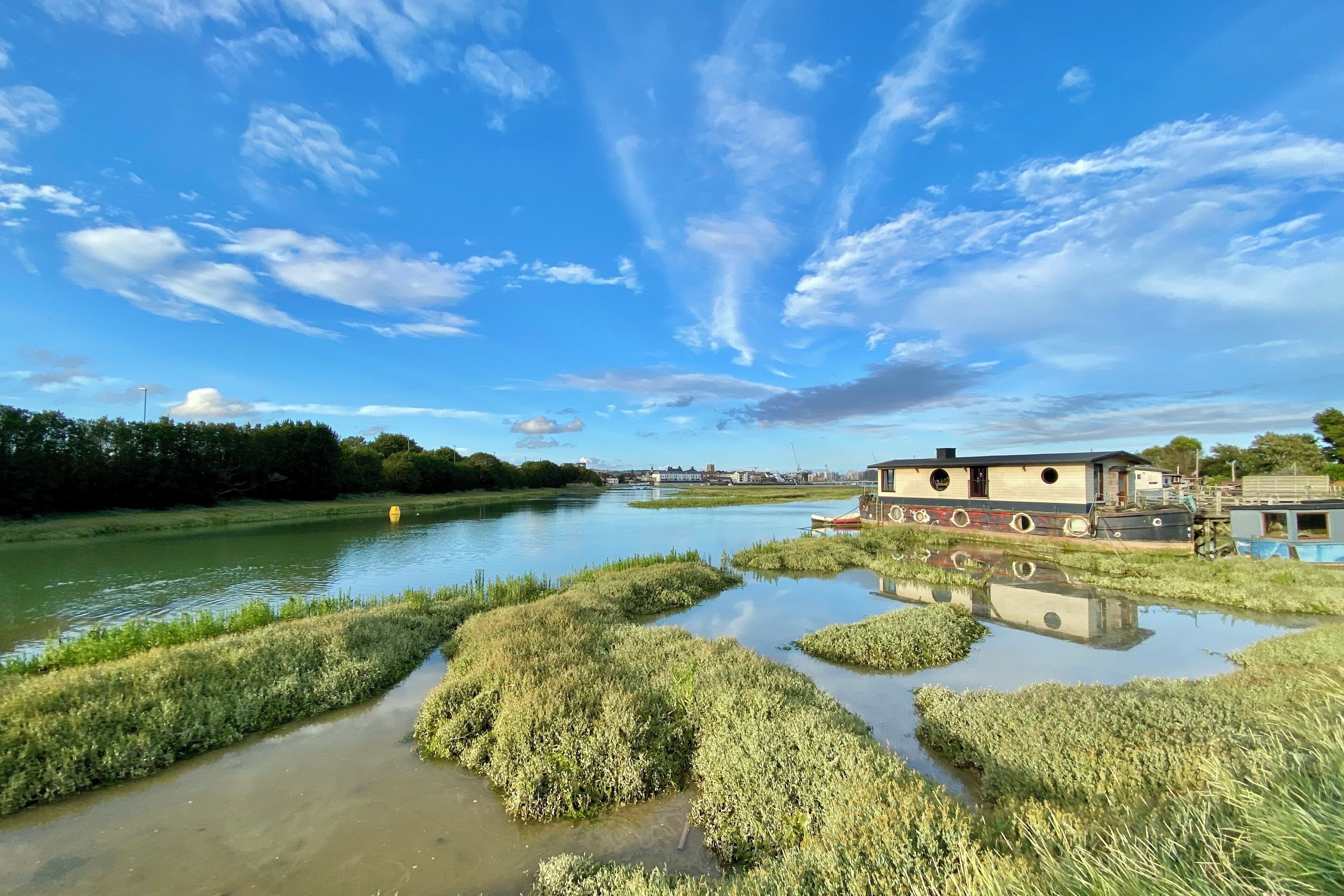 Vista sul fiume con una casetta galleggiante e un piccolo edificio vicino all'acqua.